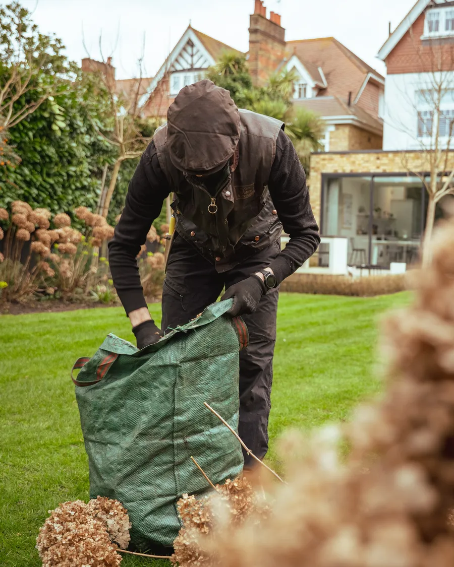 A gardener clearing garden waste on a cleared plot